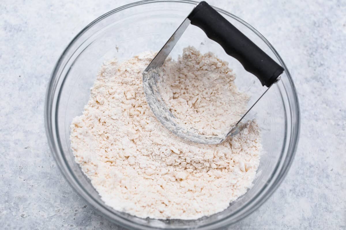 Sugar cream pie, or Hoosier pie, is a creamy, delicious treat with deep roots in the Midwest, especially in Indiana. You can top it however you like, serve it warm, at room temperature, or even chilled. Give this simple recipe a go. I know youโll love it! Overhead shot of crust ingredients in glass bowl with pastry cutter.