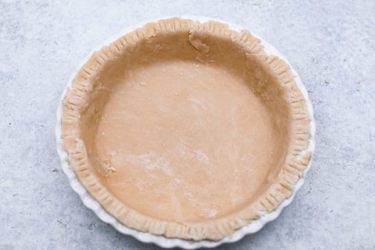 Sugar cream pie, or Hoosier pie, is a creamy, delicious treat with deep roots in the Midwest, especially in Indiana. You can top it however you like, serve it warm, at room temperature, or even chilled. Give this simple recipe a go. I know youโll love it! Overhead shot of pie crust crimped edges in a pie pan.