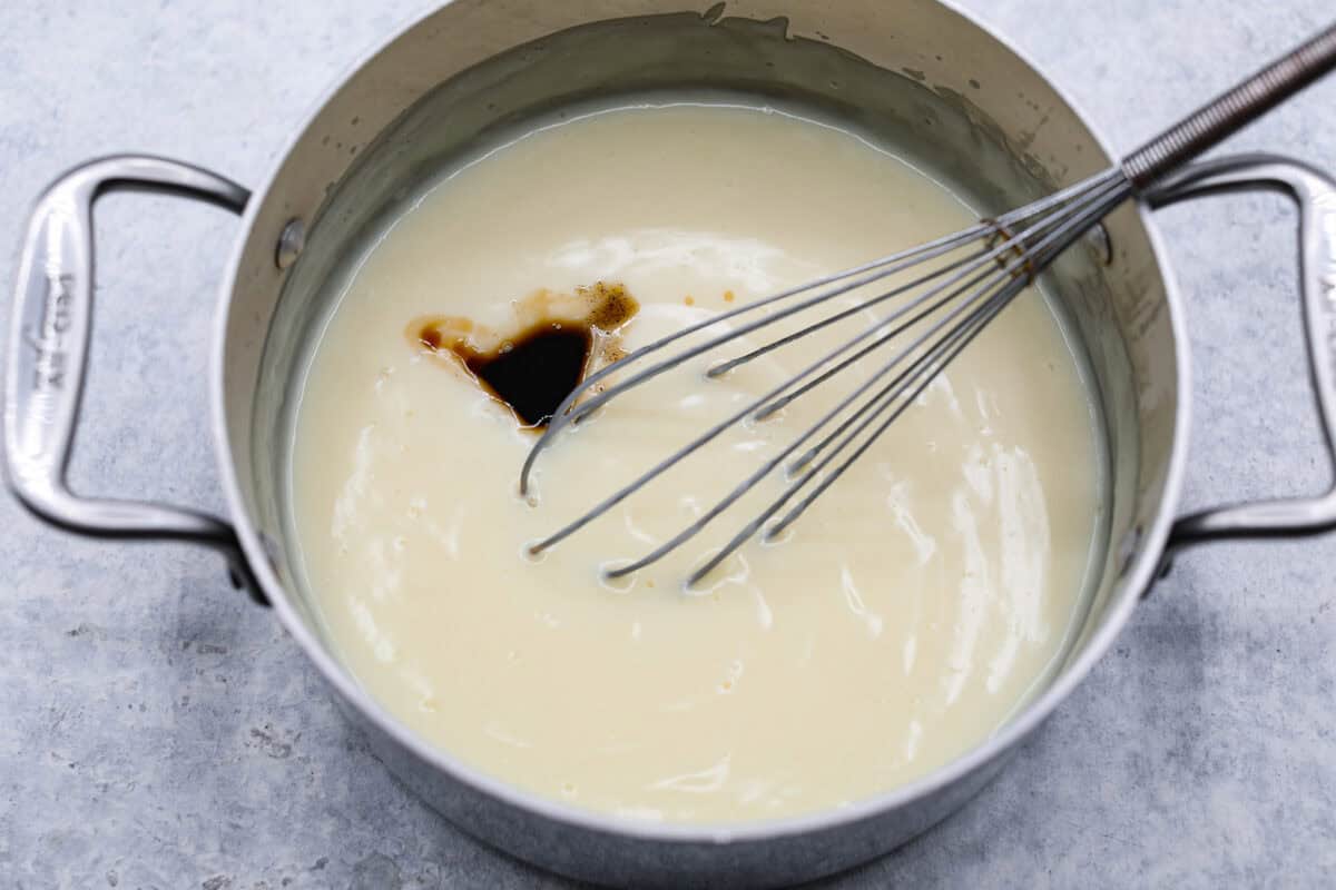 Sugar cream pie, or Hoosier pie, is a creamy, delicious treat with deep roots in the Midwest, especially in Indiana. You can top it however you like, serve it warm, at room temperature, or even chilled. Give this simple recipe a go. I know youโll love it! Overhead shot of cooked pie filling in pot with vanilla extract in it.