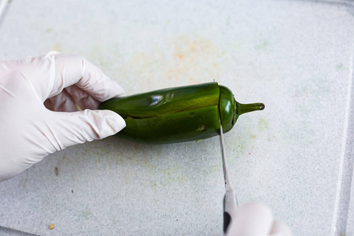 Texas Twinkies are a major upgrade to your classic jalapeรฑo poppers! They're jalapeรฑos filled with cream cheese, brisket, and shredded cheese, then wrapped in bacon and cooked to perfection. These are the hit of any party! Overhead shot of how to cut jalapeรฑos.