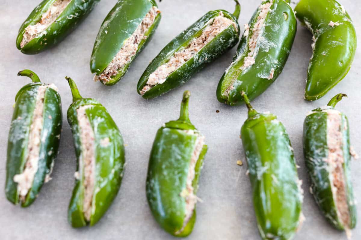 Texas Twinkies are a major upgrade to your classic jalapeรฑo poppers! They're jalapeรฑos filled with cream cheese, brisket, and shredded cheese, then wrapped in bacon and cooked to perfection. These are the hit of any party! Overhead shot of stuffed jalapeรฑos.