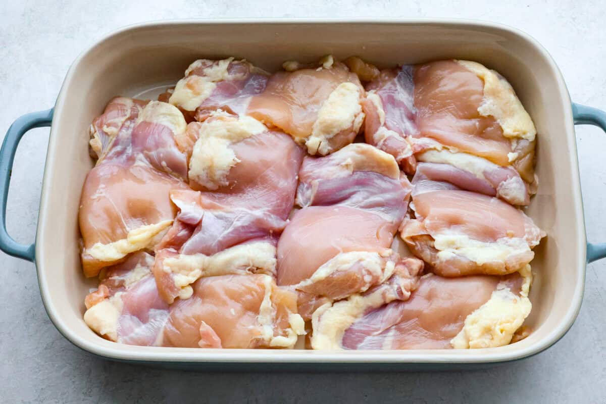 Baked Huli Huli chicken is a tried and true recipe now made in the oven! Tender chicken baked in a sweet and savory sauce. This easy one-pan dinner is full of Hawaiian-inspired flavors! Second photo of the chicken thighs in the pan.