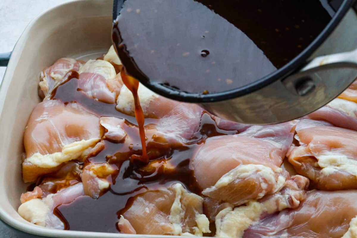 Baked Huli Huli chicken is a tried and true recipe now made in the oven! Tender chicken baked in a sweet and savory sauce. This easy one-pan dinner is full of Hawaiian-inspired flavors! Third photo of the sauce pouring over the chicken.