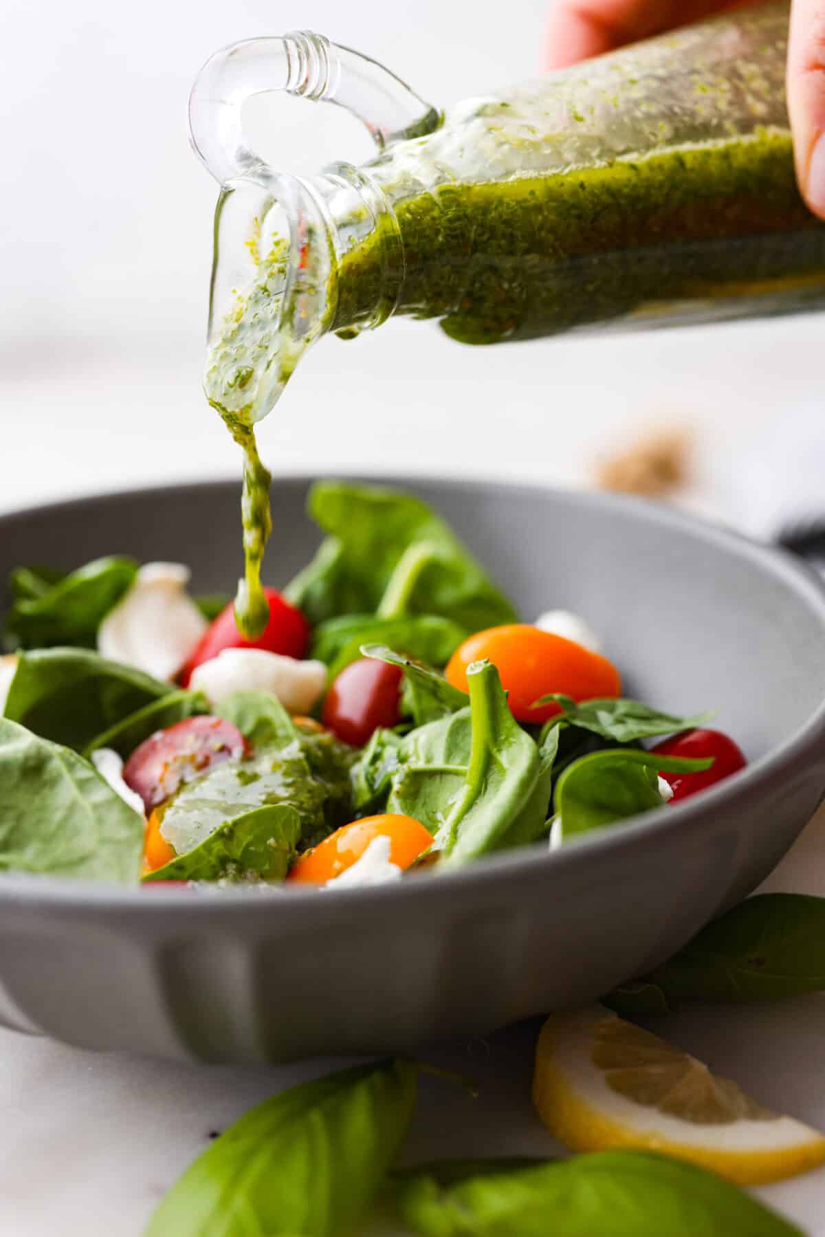 Basil Vinaigrette is a versatile dressing made from a few fresh ingredients. It is bursting with flavor and can be used on salads, as a marinade, or as a sauce for various dishes. It will be a great addition to your repertoire of homemade dressings. Side shot of basil vinaigrette being poured over a green salad.