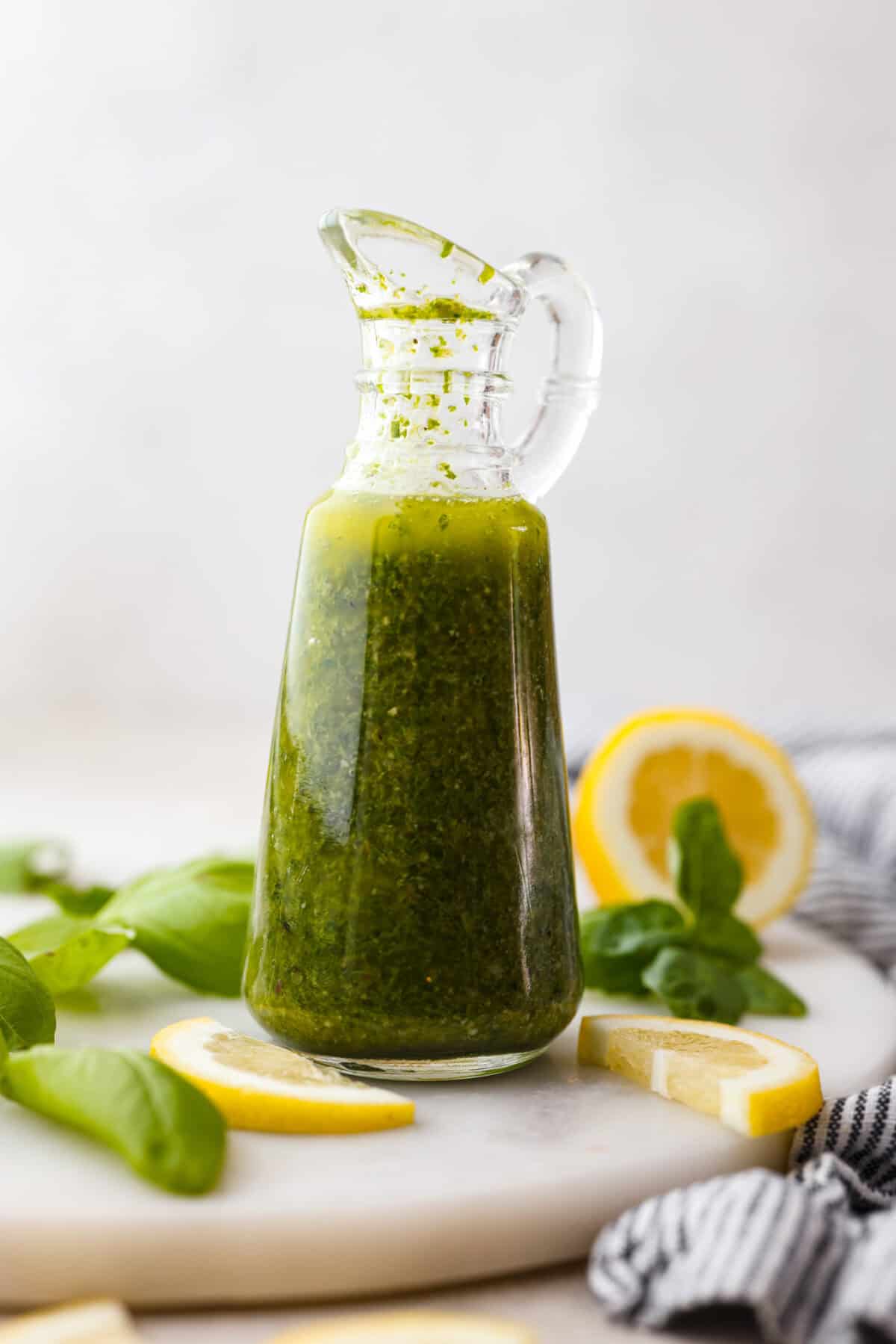 Basil Vinaigrette is a versatile dressing made from a few fresh ingredients. It is bursting with flavor and can be used on salads, as a marinade, or as a sauce for various dishes. It will be a great addition to your repertoire of homemade dressings. Side view of cute glass container with basil vinaigrette in side.