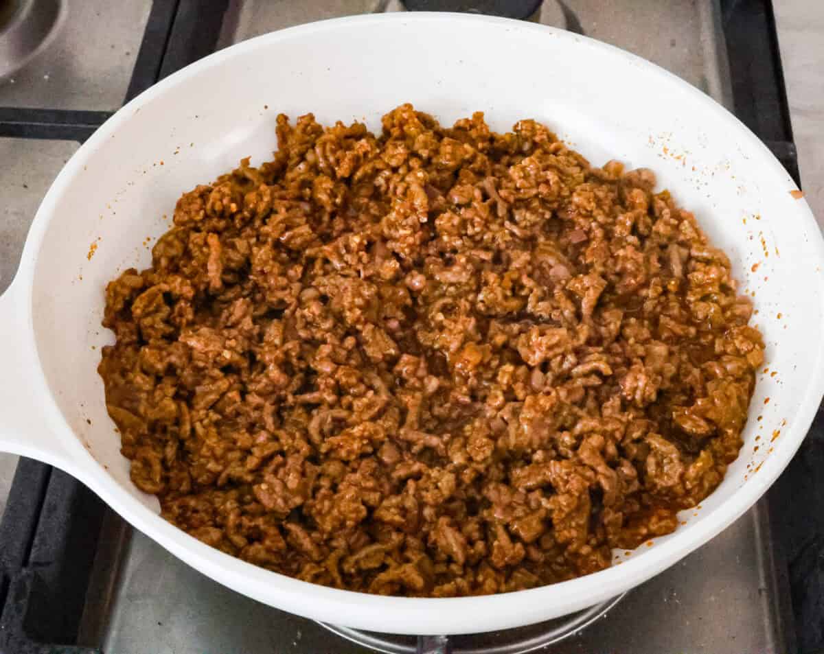 Beef taco salad is a delicious and simple family favorite, perfect for summer evenings! Packed with your favorite taco essentials like beans, corn, avocado, and fresh cilantro, it's bursting with flavor and sure to become a staple dish! Angle shot of cooked and seasoned ground beef in pan.
