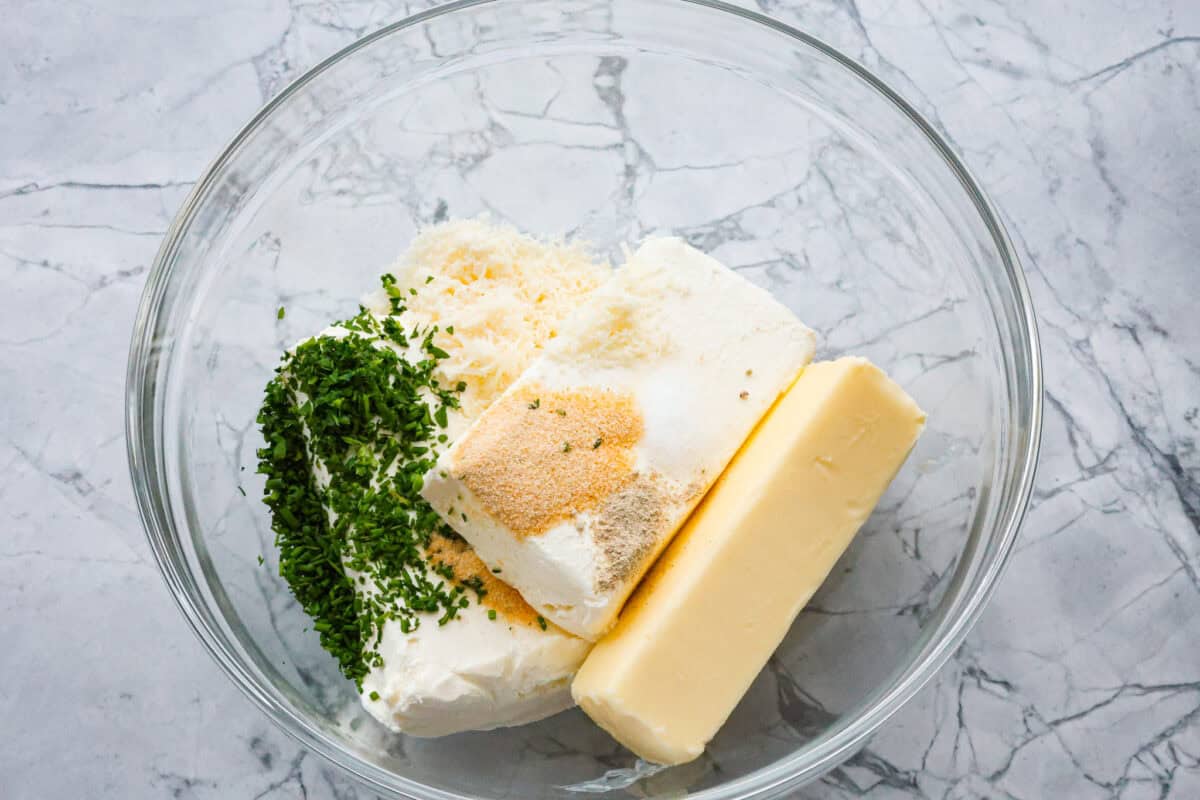 Boursin cheese is soft, creamy, and bursting with herbal flavor. Its texture is similar to cream cheese, making it incredibly versatile. It shines as a dip, enhances pasta dishes, complements meats, enriches sauces and soups, and so much more! Overhead shot of ingredients dumped into a large glass bowl.