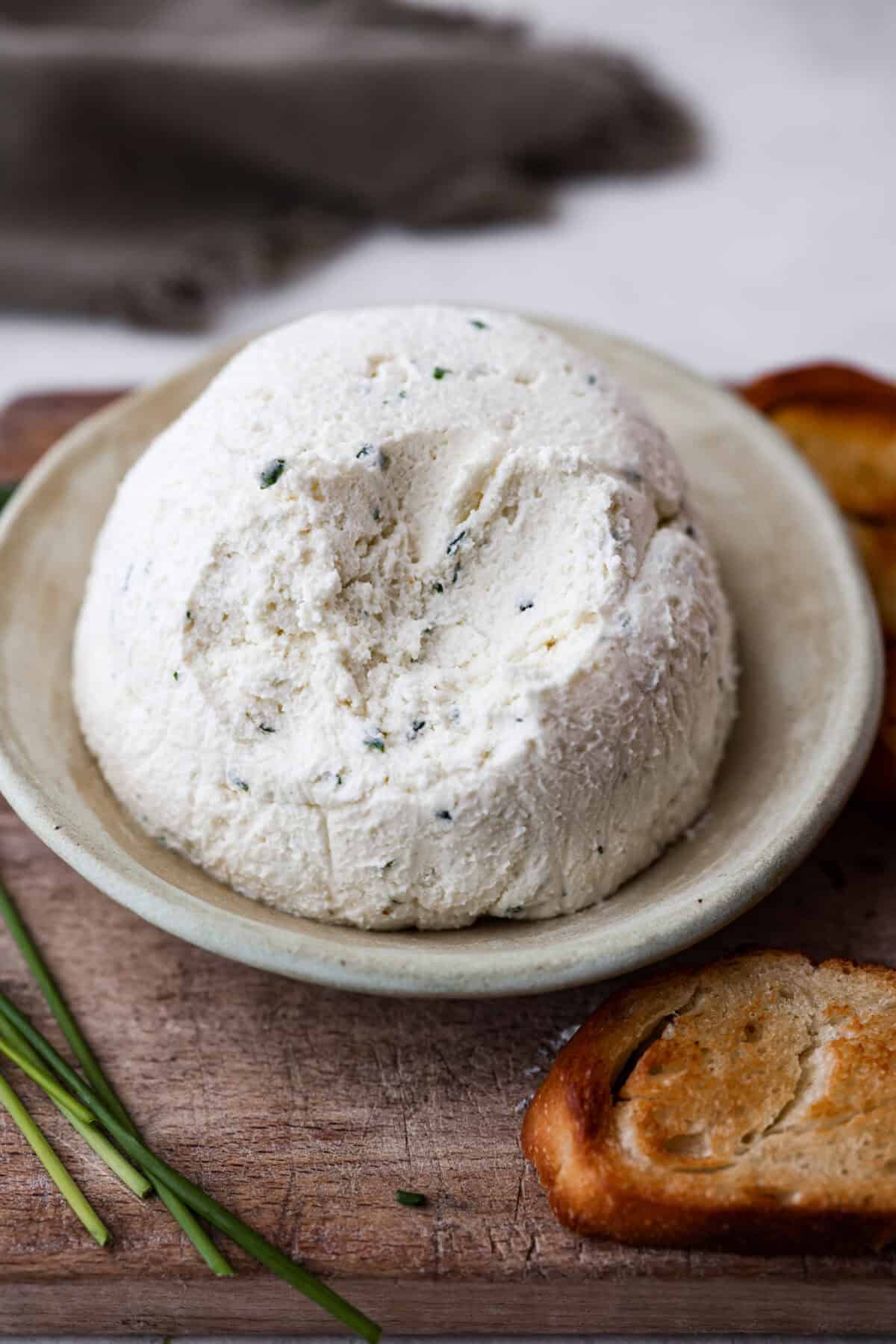Boursin cheese is soft, creamy, and bursting with herbal flavor. Its texture is similar to cream cheese, making it incredibly versatile. It shines as a dip, enhances pasta dishes, complements meats, enriches sauces and soups, and so much more! Angle shot of ball of Boursin cheese with some scoops taken out of it.