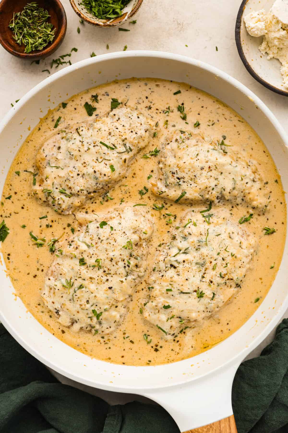 Boursin Pork Chops are savory, tender, and covered in a delicious cheesy cream sauce. This one-pan recipe is the perfect easy main that can be on your dinner table in just 30 minutes! Overhead shot of cooked Boursin pork chops in pan.