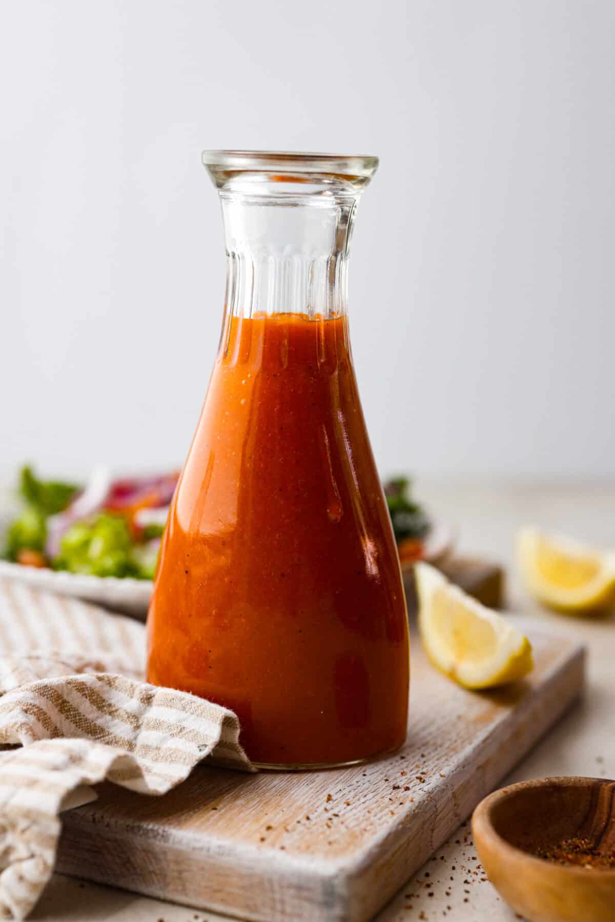 Delicious Catalina French Dressing will give your salad the perfect tangy, sweet flavor! It comes together quickly with a few simple ingredients you probably already have in your kitchen! Once you try it, you will want to have it on repeat! Side shot of Catalina French dressing in a glass bottle.