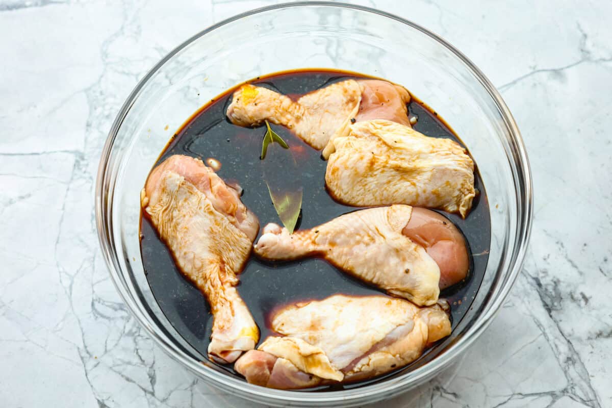 Chicken Adobo is a tangy, salty, sweet, and spicy Filipino dish. This meal is easy to make and requires just a few simple ingredients. It's sure to become a family favorite! Overhead shot of raw chicken in marinade in large bowl.