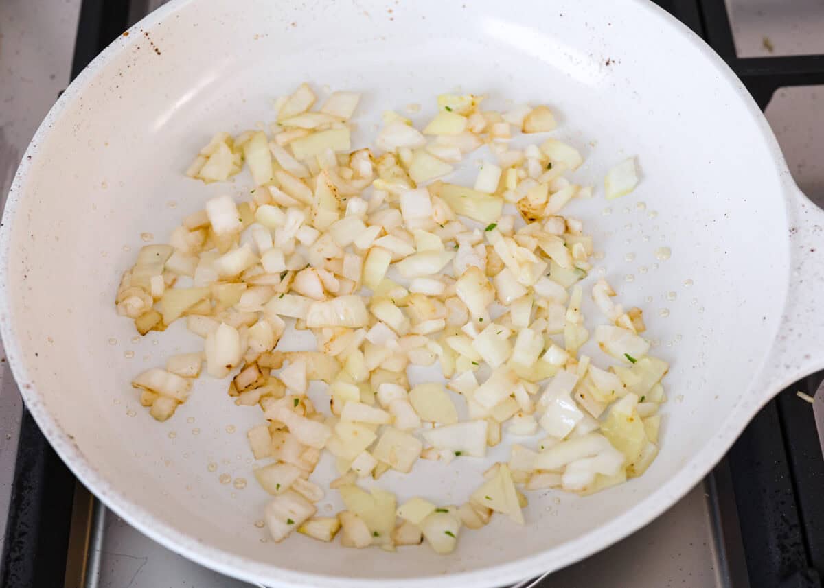 Chicken Adobo is a tangy, salty, sweet, and spicy Filipino dish. This meal is easy to make and requires just a few simple ingredients. It's sure to become a family favorite! Angle shot of diced onions being sautรฉed in a skillet.