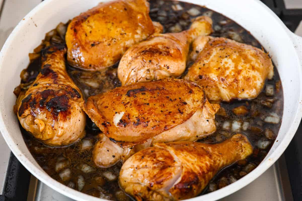 Chicken Adobo is a tangy, salty, sweet, and spicy Filipino dish. This meal is easy to make and requires just a few simple ingredients. It's sure to become a family favorite! Angel shot of chicken in sauce, simmering in a skillet.