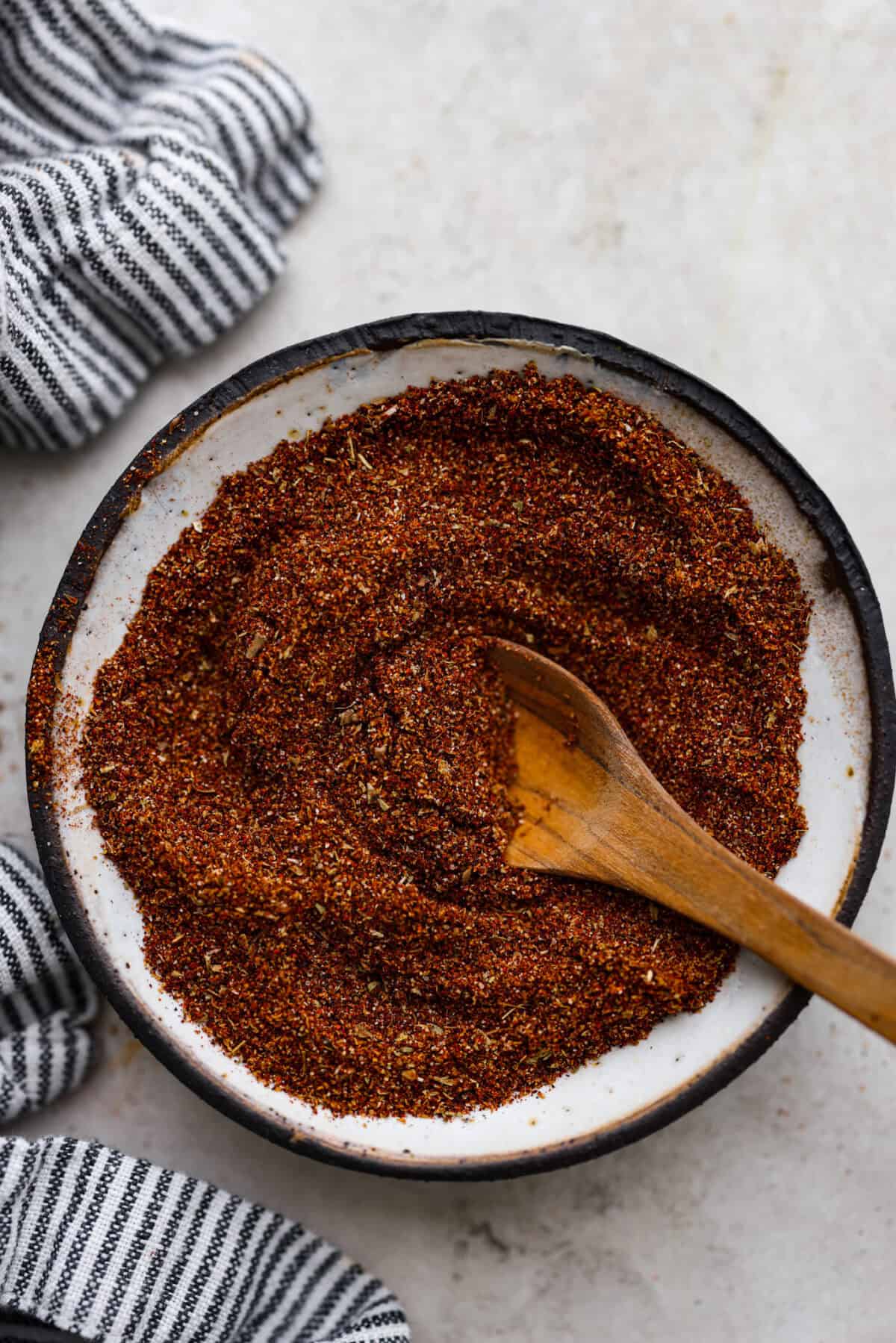 Enjoy a perfect blend of smoky and spicy flavors with this homemade Chipotle Seasoning! Featuring bold spices like chipotle powder, paprika, cumin, garlic powder, oregano, and more, this mix delivers a major flavor boost. Try it on everything from chicken to ground beef! Overhead shot of mixed chipotle seasoning with wooden spoon in it.