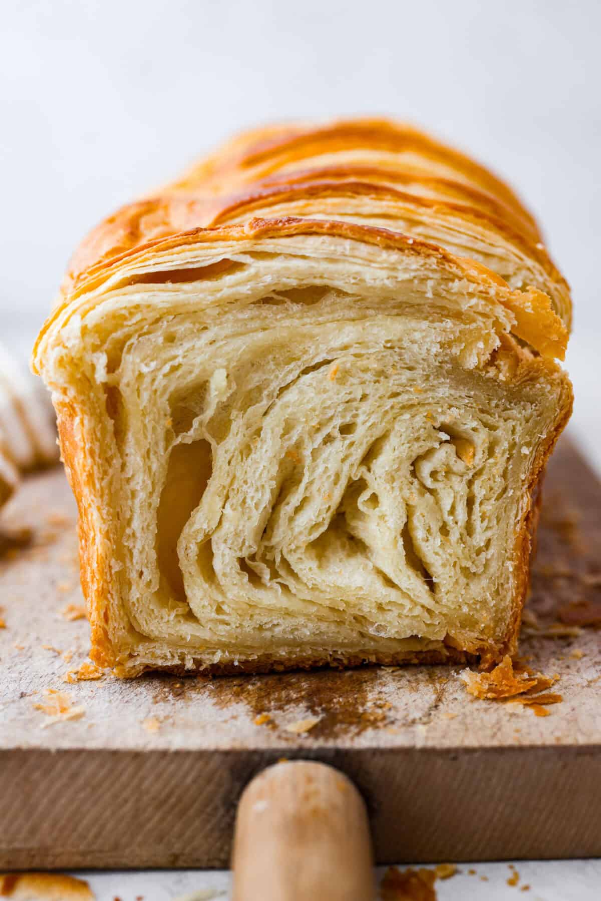 Croissant Bread is beautiful and fluffy with crispy, flaky layers on the outside. It's also one of the most delicious breads you'll ever taste - it will be love at first bite! Add it to your next brunch spread and use it to make French toast, sandwiches, and breakfast casseroles! Side shot of croissant loaf sliced down the middle.