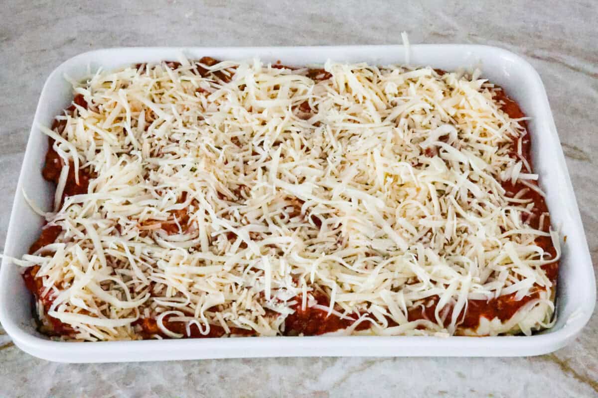 Eggplant Lasagna is a delicious low-carb way to enjoy the classic flavors of lasagna! The tender eggplant layers are loaded with meat sauce, a creamy ricotta mixture, and lots of melty cheese. You won't even miss the noodles! Sixth photo of the cheese sprinkled on top before baking.