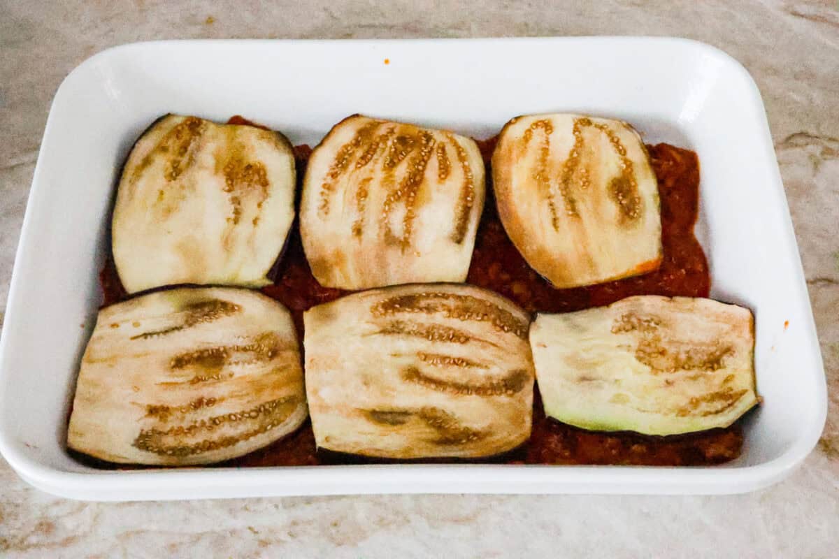 Eggplant Lasagna is a delicious low-carb way to enjoy the classic flavors of lasagna! The tender eggplant layers are loaded with meat sauce, a creamy ricotta mixture, and lots of melty cheese. You won't even miss the noodles! Fifth photo of the layering of the eggplant lasagna in the casserole dish.