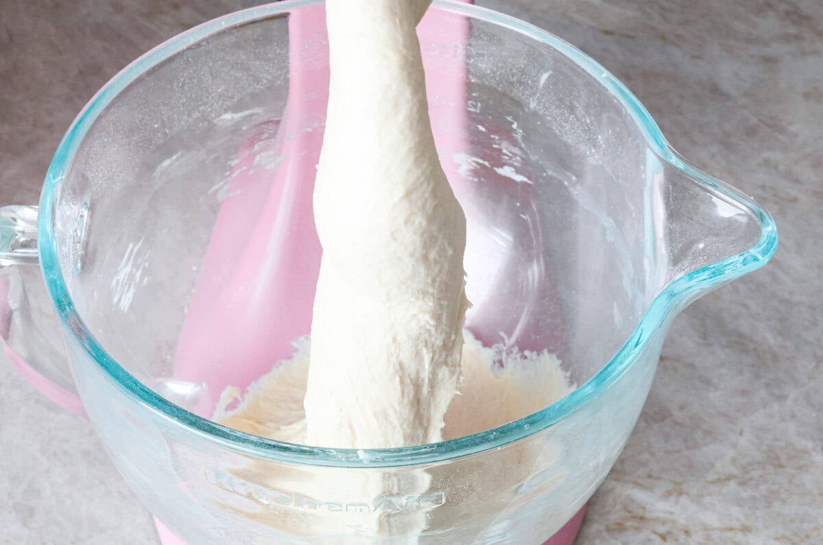 This French baguette recipe is super easy and will change your life! It has a perfect crusty outside and tender, soft inside, perfect for your bread cravings. Angle shot of dough being mixed in stand mixer.