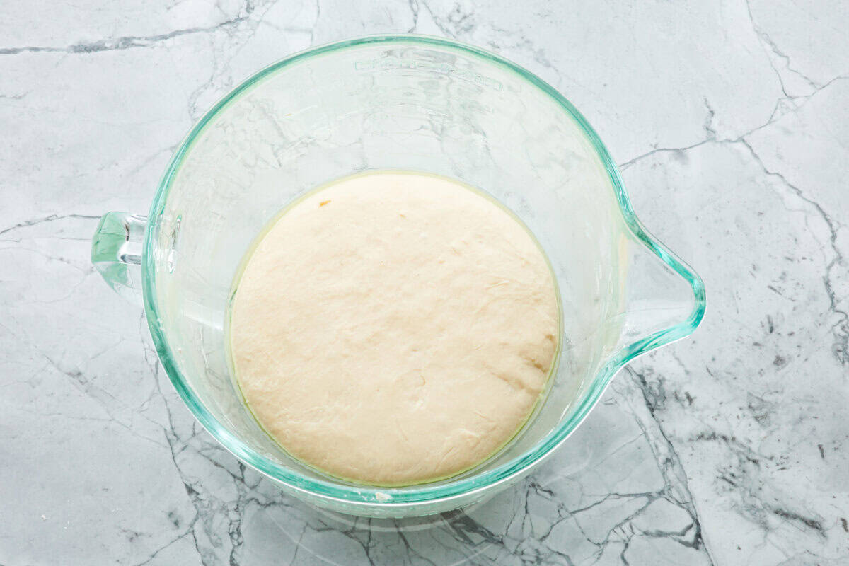 This French baguette recipe is super easy and will change your life! It has a perfect crusty outside and tender, soft inside, perfect for your bread cravings. Overhead shot of dough in an oiled bowl.