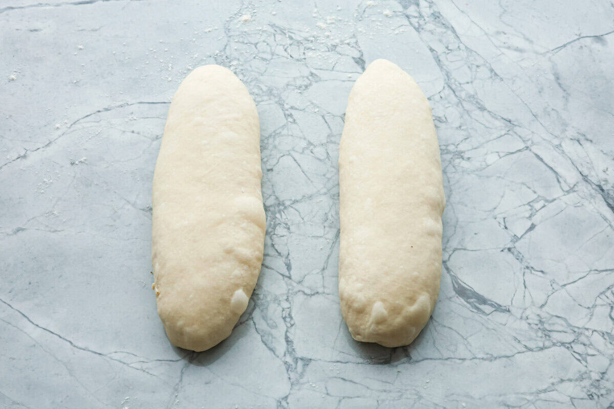 This French baguette recipe is super easy and will change your life! It has a perfect crusty outside and tender, soft inside, perfect for your bread cravings. Overhead shot of two dough loafs.
