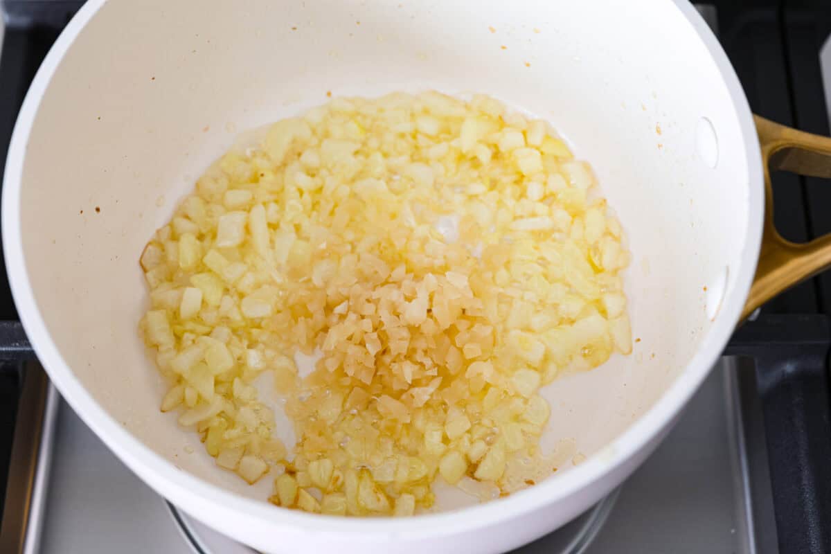 Garlic Butter Rice is the perfect side dish for dinner! A simpleย mix of butter, sautรฉed onion, garlic, and chicken brothย gives this rice tons of great flavor. It's easy to make and tastes amazing! Overhead host of butter and onion mixture with garlic on top.