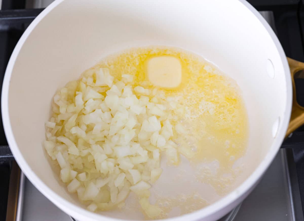 Garlic Butter Rice is the perfect side dish for dinner! A simpleย mix of butter, sautรฉed onion, garlic, and chicken brothย gives this rice tons of great flavor. It's easy to make and tastes amazing! Overhead shot of melted butter and onions in a pot on the stove.