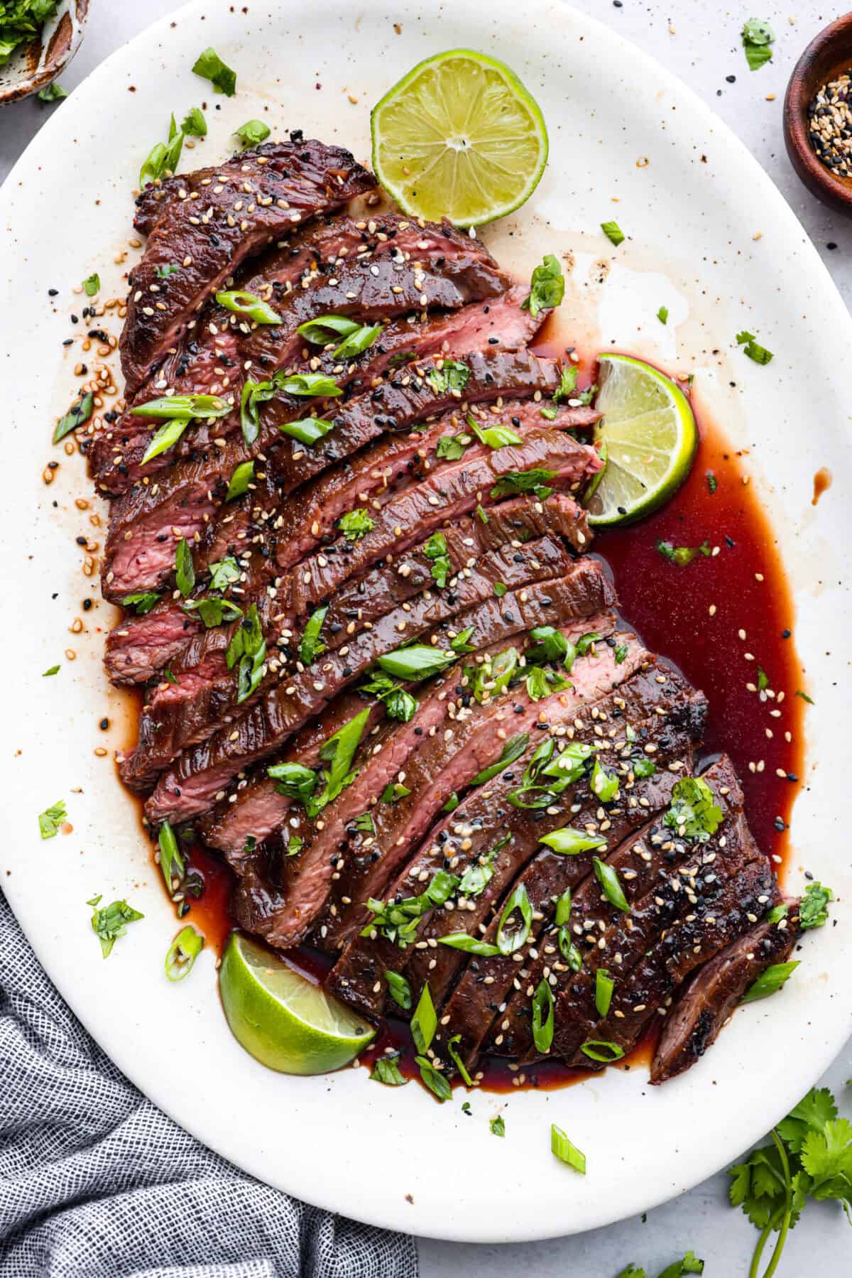 This grilled flank steak with Asian-inspired marinade features a savory blend of soy sauce, ginger, and garlic. The steak is seared to perfection on a hot grill, locking in all the delicious flavors. Best of all, itโs ready in less than 10 minutes! Overhead shot of flank steak sliced up limes on the side