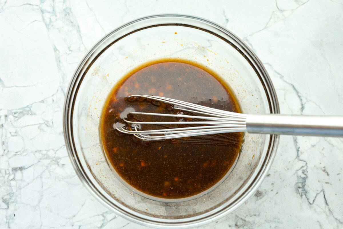 This grilled flank steak with Asian-inspired marinade features a savory blend of soy sauce, ginger, and garlic. The steak is seared to perfection on a hot grill, locking in all the delicious flavors. Best of all, itโs ready in less than 10 minutes! Overhead shot of marinade ingredients mixed in a bowl, with a whisk.