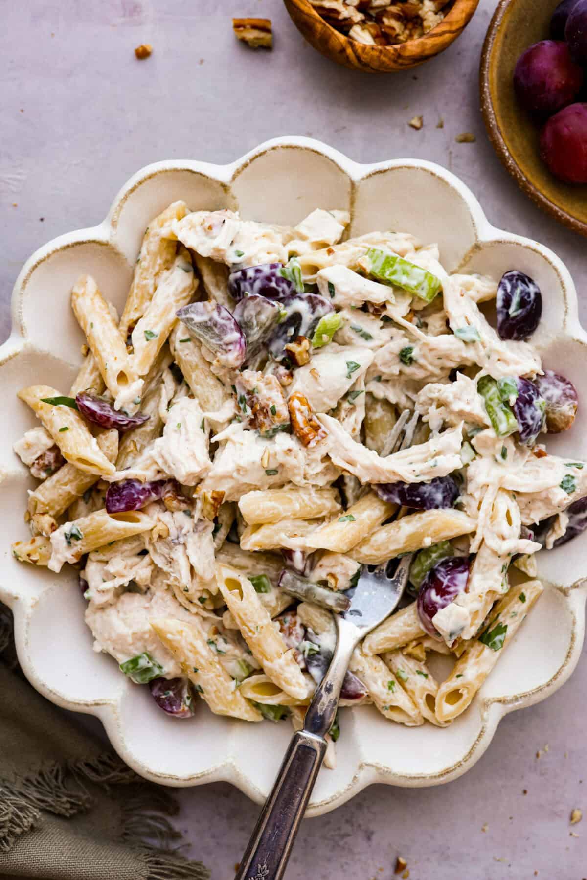 This healthy chicken pasta salad is a fun twist on the classic sandwich recipe. It's filled with penne pasta, tender chunks of chicken breast, crunchy pecans, all tossed in a creamy, sweet dressing. It's the perfect blend of flavors and textures. Overhead shot of a serving of pasta salad in a bowl with a fork.