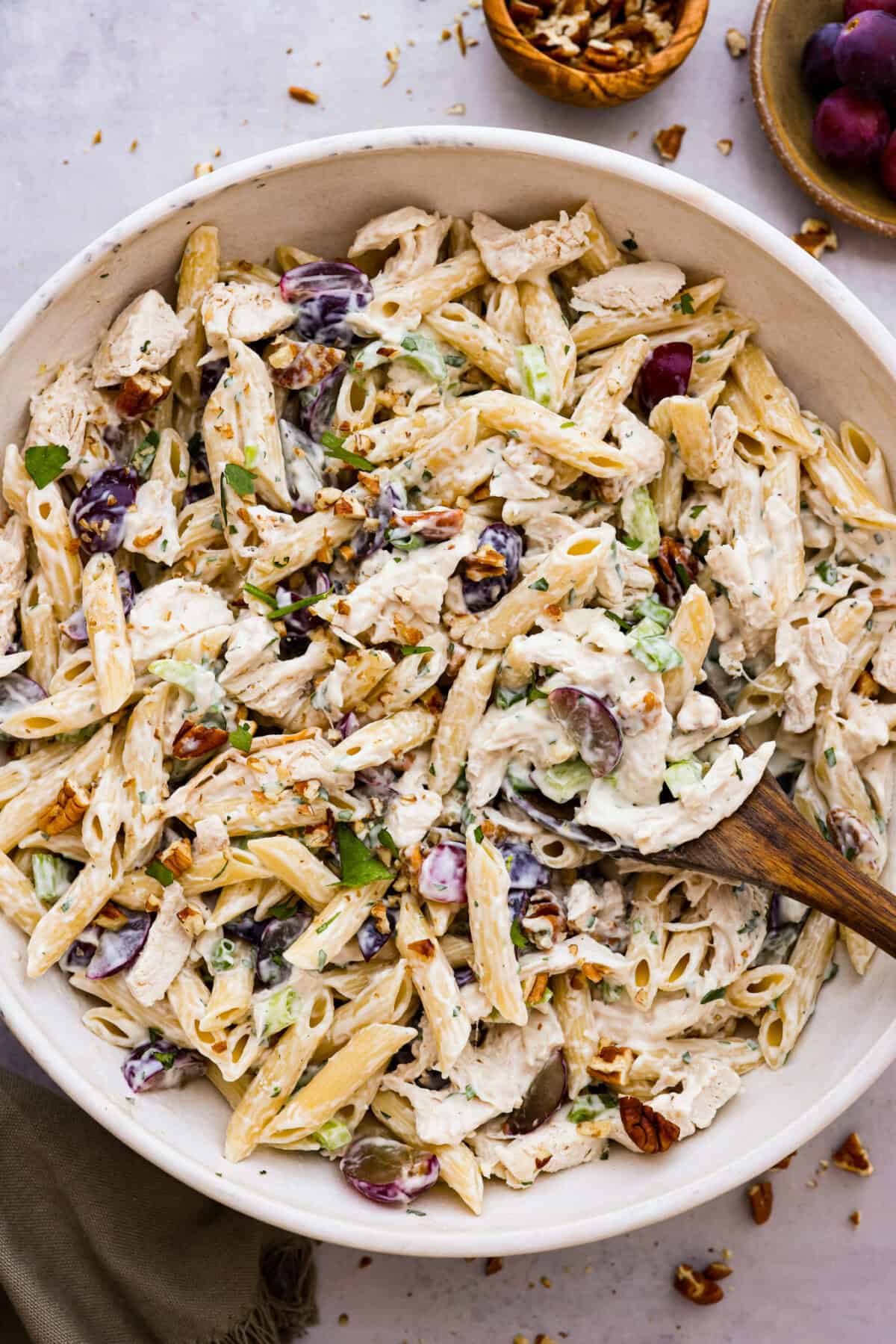 TThis healthy chicken pasta salad is a fun twist on the classic sandwich recipe. It's filled with penne pasta, tender chunks of chicken breast, crunchy pecans, all tossed in a creamy, sweet dressing. It's the perfect blend of flavors and textures. Overhead shot of a large bowl of healthy chicken pasta salad.