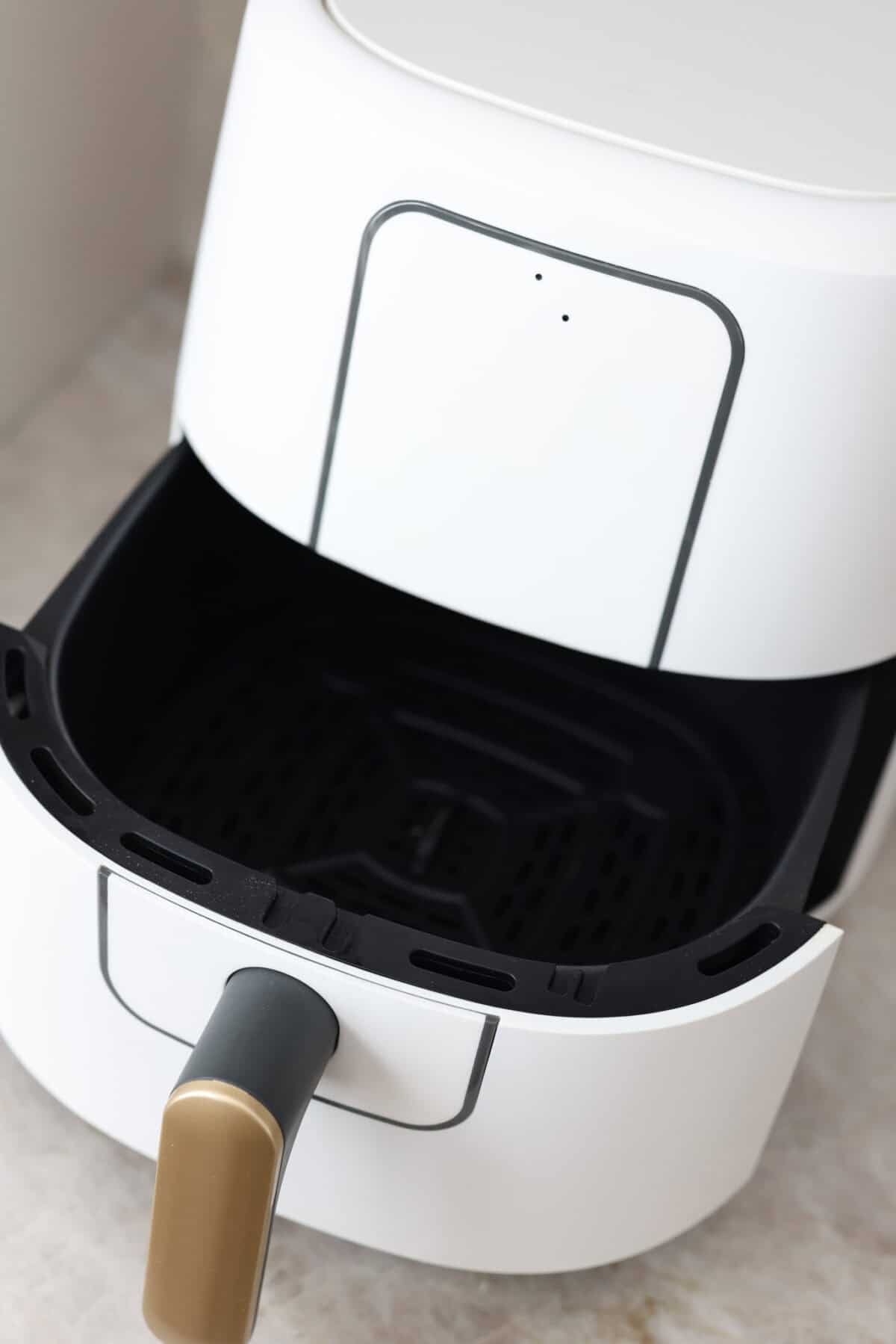 The air fryer is one of the most versatile appliances in today's kitchen! Learn how to use an air fryer to cook, reheat, and achieve that "fried" texture without frying in oil. Once you cook in the air fryer you will never look back! Close view of an air fryer with the basket open.