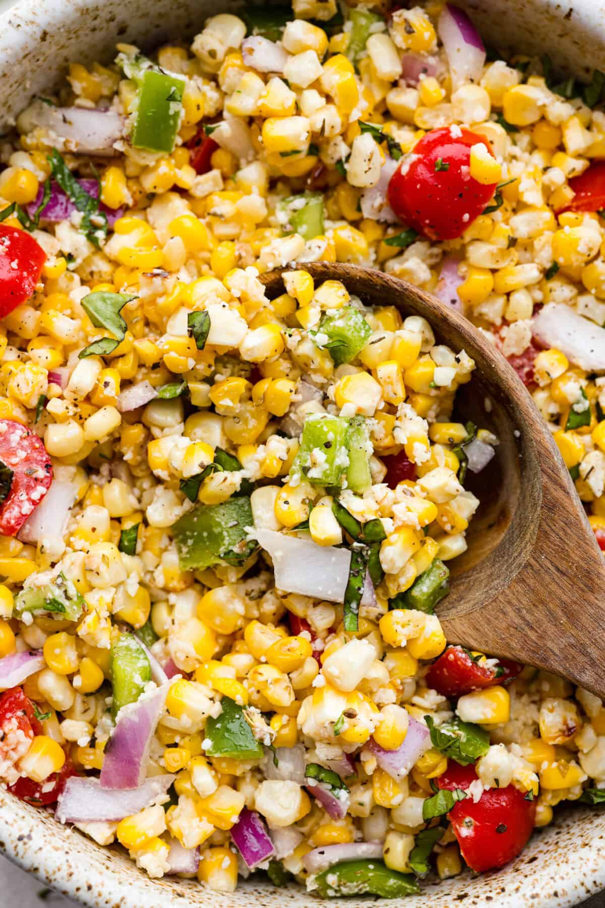 This Italian Corn Salad is bursting with fresh flavors from sweet corn, juicy grape tomatoes, crisp green bell pepper, and sharp parmesan cheese. Tossed in a zesty homemade Italian dressing, it’s perfect for summer or any time of the year. Close up shot of Italian corn salad.