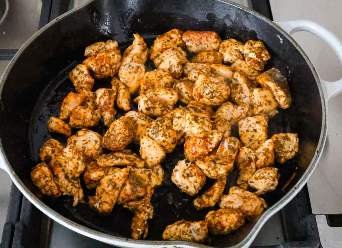 One-Pan Lemon Chicken Orzo is a comforting, well-rounded meal! Tender, juicy chicken pieces are joined with orzo pasta in a bright lemon sauce, resulting in melt-in-your-mouth deliciousness! Your whole family will adore this tasty dinner! Angle shot of pieces of seasoned chicken being seared in a pan.