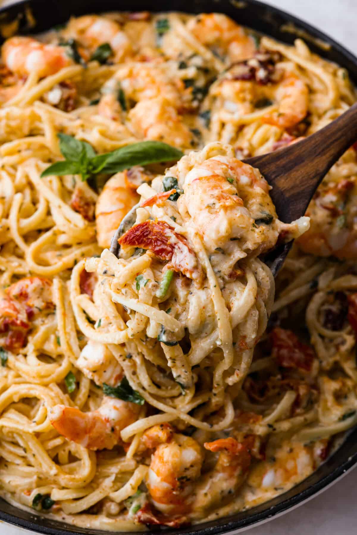 Marry Me Shrimp Pasta dazzles with robust Italian flavors. It's ready in just 30 minutes, and the creamy sauce, brimming with fresh herbs and spices, could very well lead to a marriage proposal after your first bite! Angle shot of close up pasta with scoop being taken out of it.