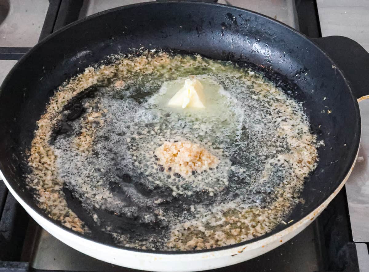 Marry Me Shrimp Pasta dazzles with robust Italian flavors. It's ready in just 30 minutes, and the creamy sauce, brimming with fresh herbs and spices, could very well lead to a marriage proposal after your first bite! Angle shot of but and garlic sautรฉing in a skillet.
