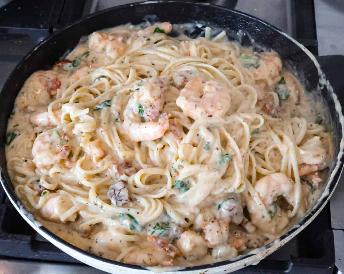 Marry Me Shrimp Pasta dazzles with robust Italian flavors. It's ready in just 30 minutes, and the creamy sauce, brimming with fresh herbs and spices, could very well lead to a marriage proposal after your first bite! Angle shot of skillet with completed marry me shrimp with pasta.