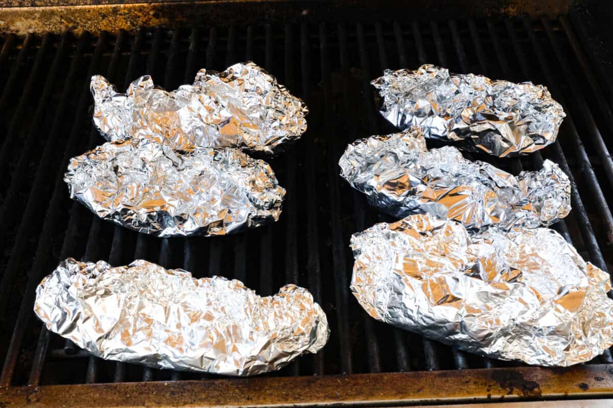 Try these delicious Philly Cheesesteak Foil Packs, a fun new way to enjoy the flavors of the classic Philly Cheesesteak. Tender beef, veggies, and melty cheese are grilled or baked together for a wonderful crowd-pleasing meal everyone will love! Angle shot of wrapped philly cheesesteak packs on grill.