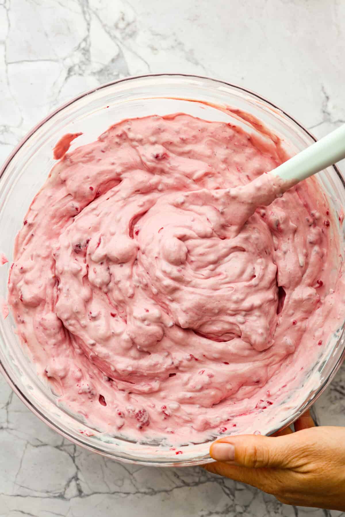Fresh and fruity Raspberry Fluff Salad is a sweet and creamy side or dessert with a mix of raspberries, vanilla yogurt and Cool Whip. Made with just 4 ingredients in 5 minutes, it's SO easy to make and perfect for potlucks and picnics! The top view of all of the ingredients mixed together in a glass bowl.