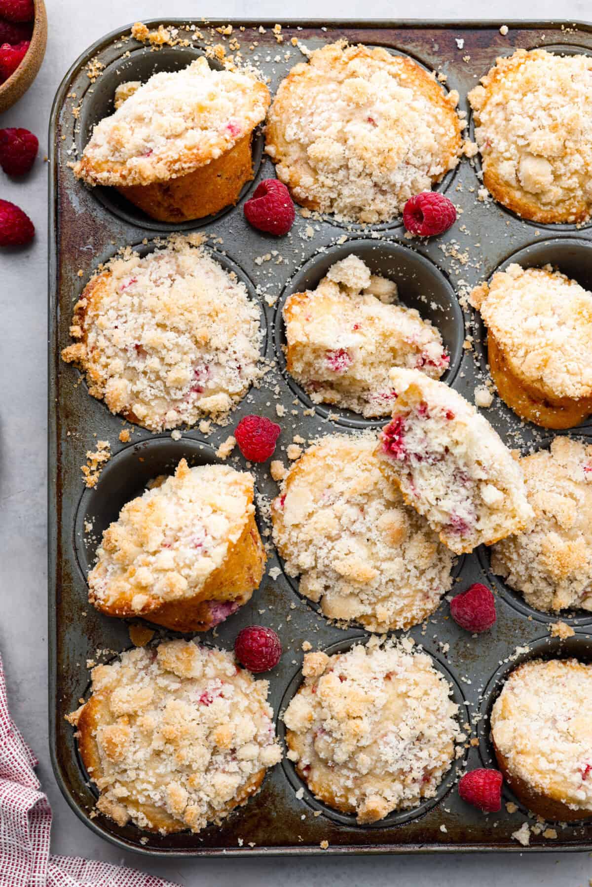 These raspberry muffins are moist and delicious, filled with plump fresh raspberries and topped with a sweet, crunchy streusel topping! They are perfect for a warm breakfast, brunch, or as an after-school or work snack. Your family will be begging for more, so donโt expect them to last long! Overhead shot of baked raspberry muffins in muffin tin.