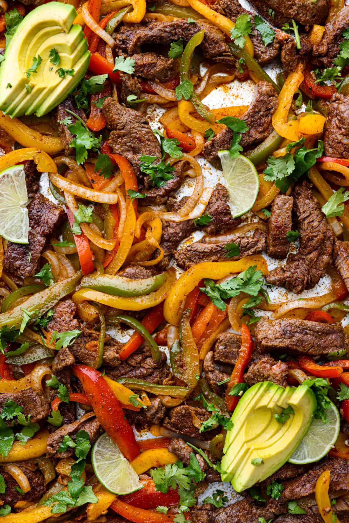 Sheet pan steak fajitas are beautiful and bursting with flavor. Easy to throw together on busy weeknights, they feature tender steak and crisp, colorful vegetables in every bite. You will definitely want to add this to your weekly meal planning! Close up shot of sheet pan steak fajitas.