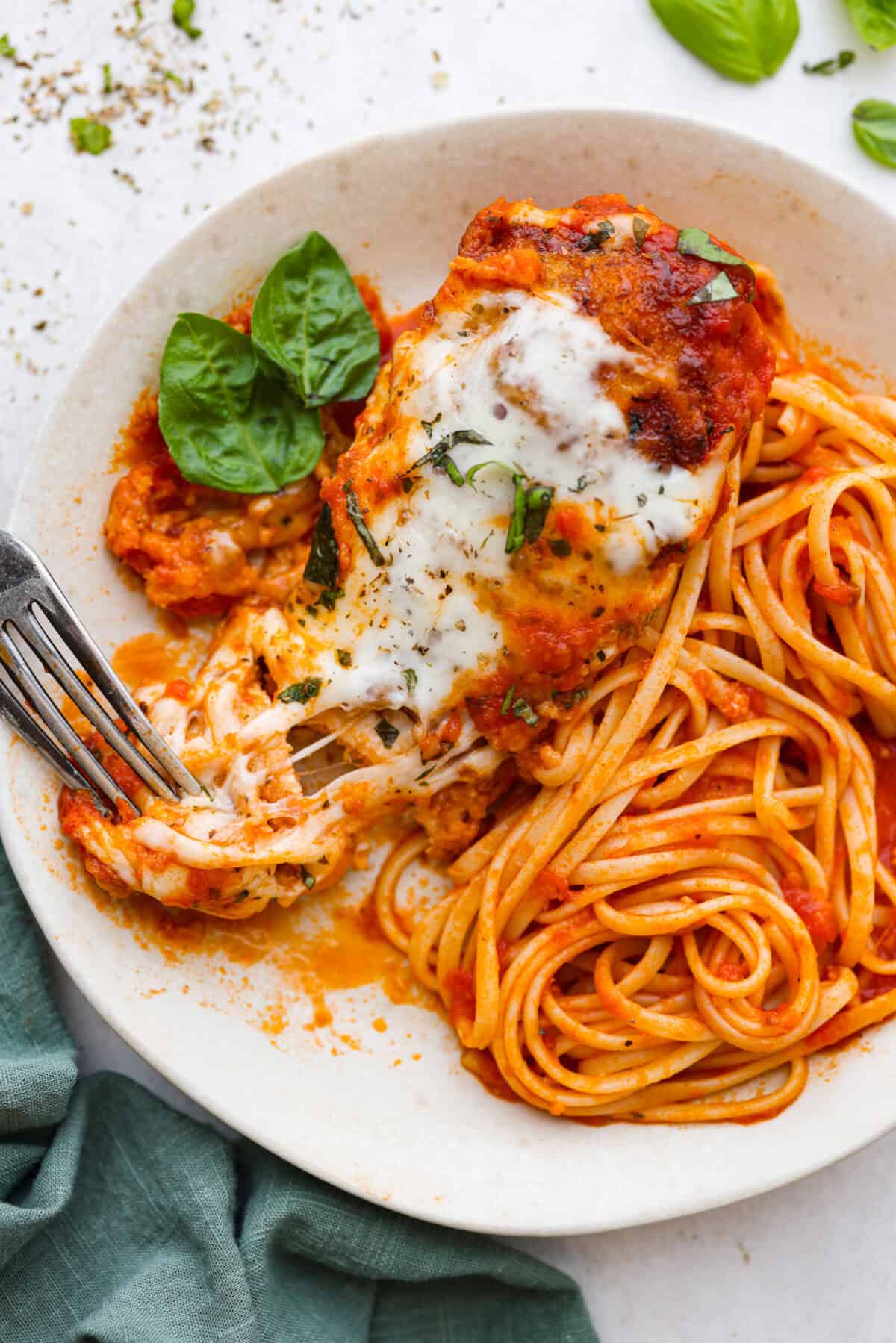 This simple slow-cooker chicken parmesan is full of delicious Italian flavors, oozy cheese, and mouthwatering marinara sauce. You'll be able to throw everything in the crock pot, set it, and forget it—dinner is served! Overhead shot of plated slow cooker chicken parmesan over noodles.