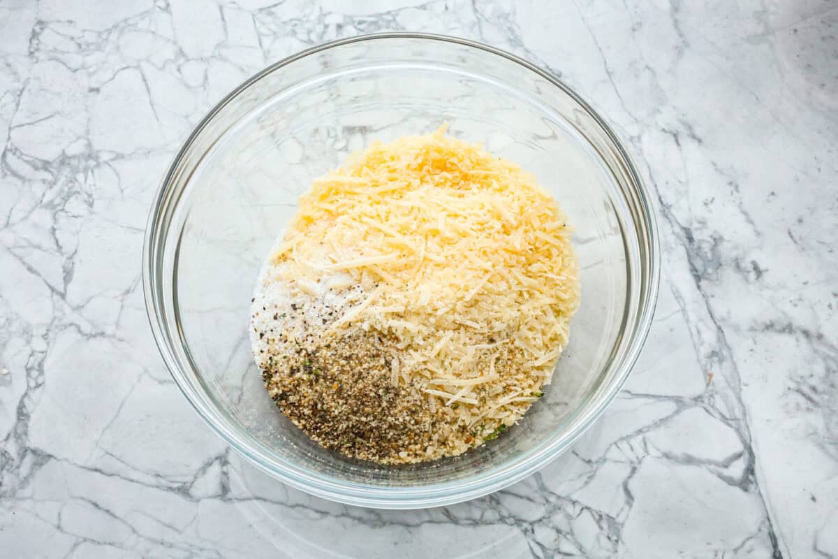 This simple slow-cooker chicken parmesan is full of delicious Italian flavors, oozy cheese, and mouthwatering marinara sauce. You'll be able to throw everything in the crock pot, set it, and forget it—dinner is served! Overhead shot of breading ingredients a glass bowl.