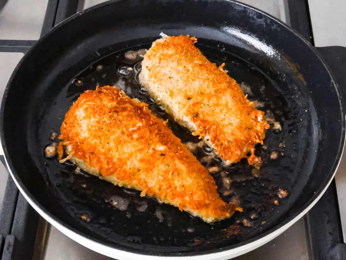 This simple slow-cooker chicken parmesan is full of delicious Italian flavors, oozy cheese, and mouthwatering marinara sauce. You'll be able to throw everything in the crock pot, set it, and forget it—dinner is served! Overhead shot of breaded chicken being fried on a skillet.