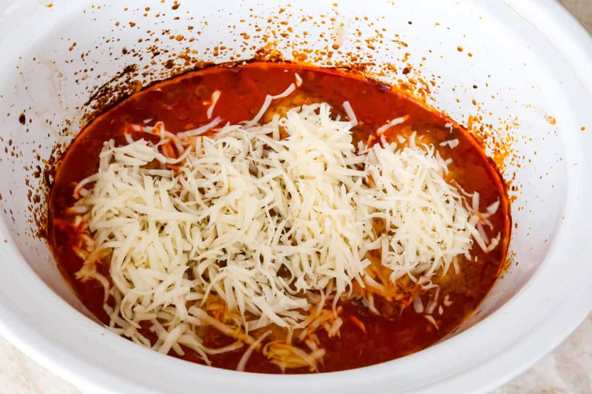 This simple slow-cooker chicken parmesan is full of delicious Italian flavors, oozy cheese, and mouthwatering marinara sauce. You'll be able to throw everything in the crock pot, set it, and forget it—dinner is served! Overhead shot of cooked chicken in bottom of marinara sauce with cheese sprinkled on top.