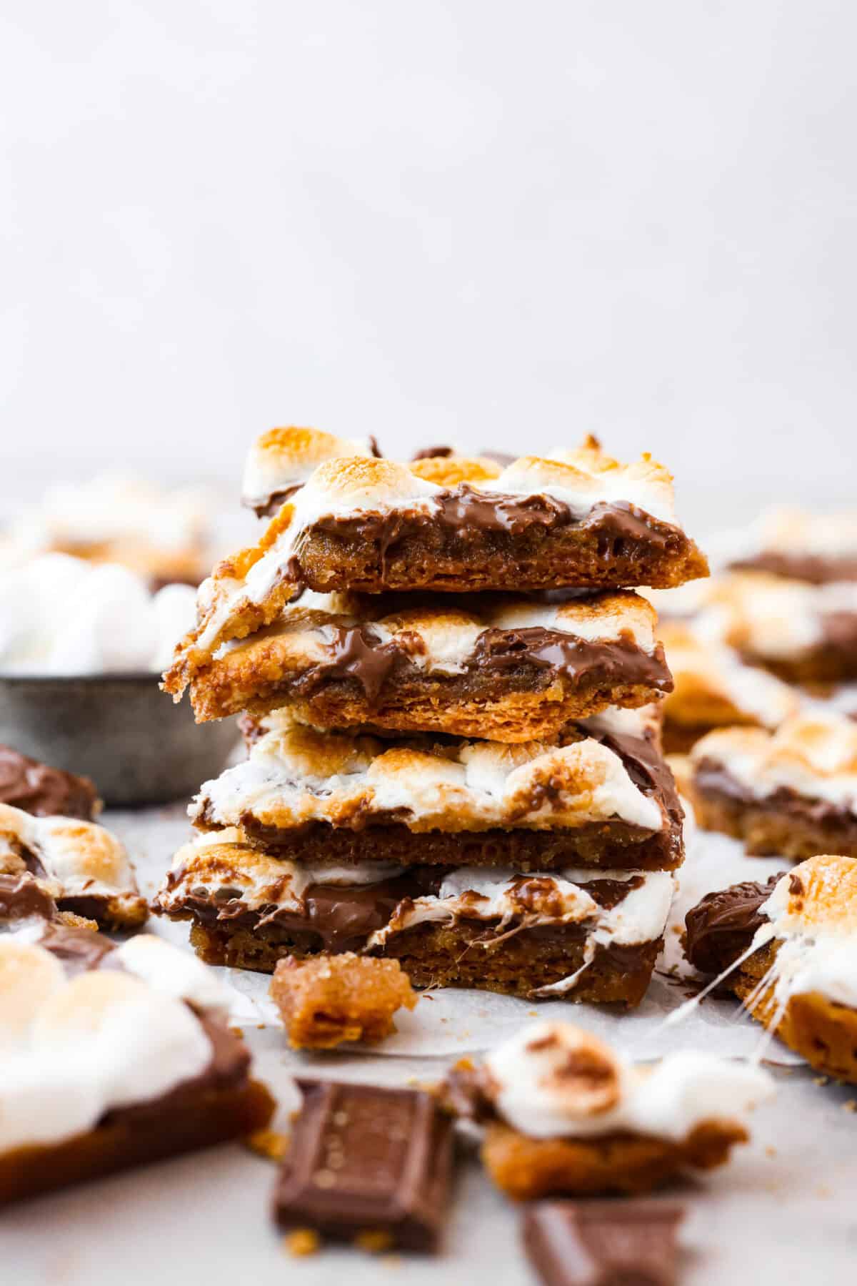 S'mores crack is a quick way to enjoy the classic s'more experience without a campfire. Featuring a buttery graham cracker crust, rich melted chocolate, and toasted marshmallows, this treat will quickly become a family favorite. Side shot of a stack of s'mores crack pieces.