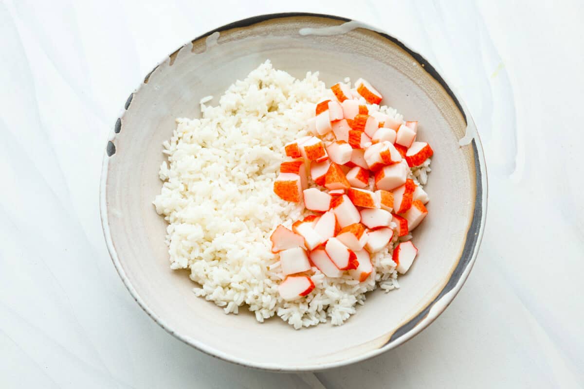 This sushi bowl is a deconstructed California sushi roll loaded with irresistible flavor and all of the best sushi ingredients. Itโs layered with sushi rice, crab, cucumber, avocado, a tasty sauce, and more. Itโs easy to make and ready to serve in just 20 minutes! Overhead shot of bowl with rice and imitation crab.