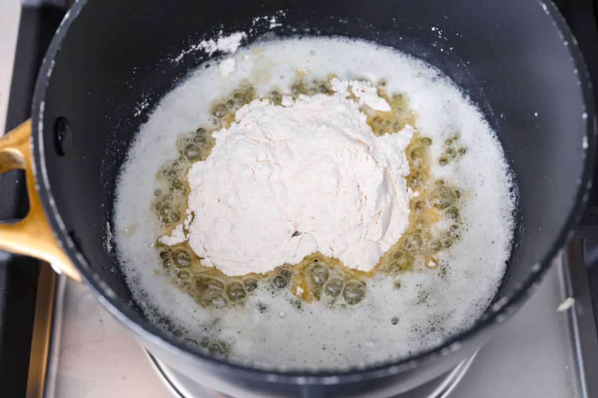 Swedish Meatball Casserole is a classic comfort meal the whole family will enjoy! Tender meatballs are layered over perfectly cooked pasta and baked in a rich, creamy gravy. This dinner recipe is easy enough to make during the week but also deliciously impressive for entertaining! Overhead shot of melted butter in the bottom of a pot with flour on top.