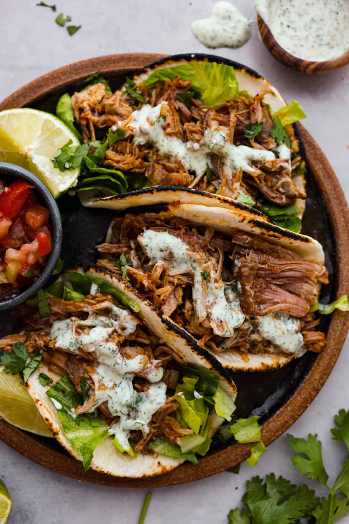 This is the BEST sweet pork taco recipe! It tastes just like Cafe Rio's famous sweet pork, with a blend of sweet and tangy flavors that melt into tender, juicy meat. It's perfect for tacos, salads, burritos, nachos, and anything else you can dream up! Overhead shot of sweet pork tacos on plate with lime wedges and pico de gallo.