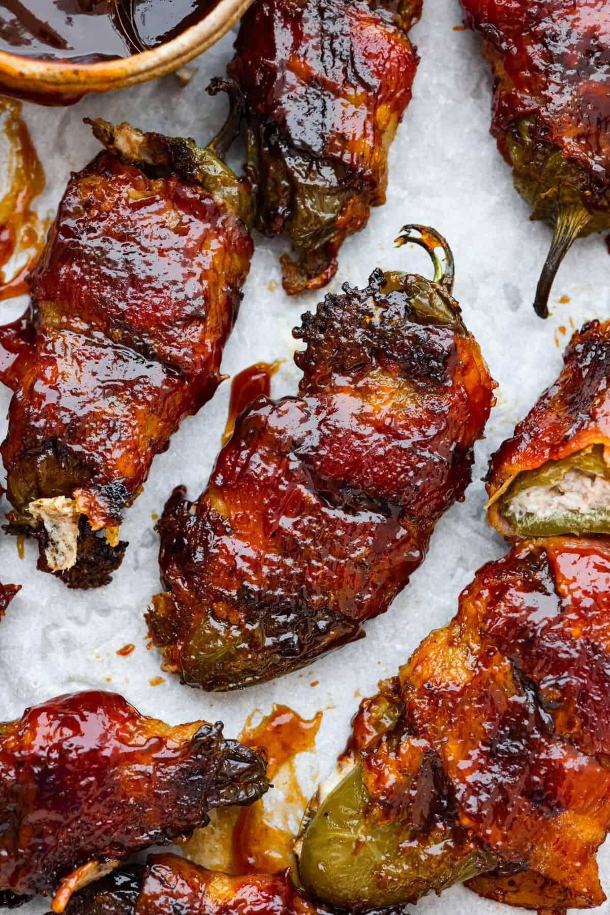 Texas Twinkies are a major upgrade to your classic jalapeรฑo poppers! They're jalapeรฑos filled with cream cheese, brisket, and shredded cheese, then wrapped in bacon and cooked to perfection. These are the hit of any party! Close up shot of cooked Texas Twinkies.