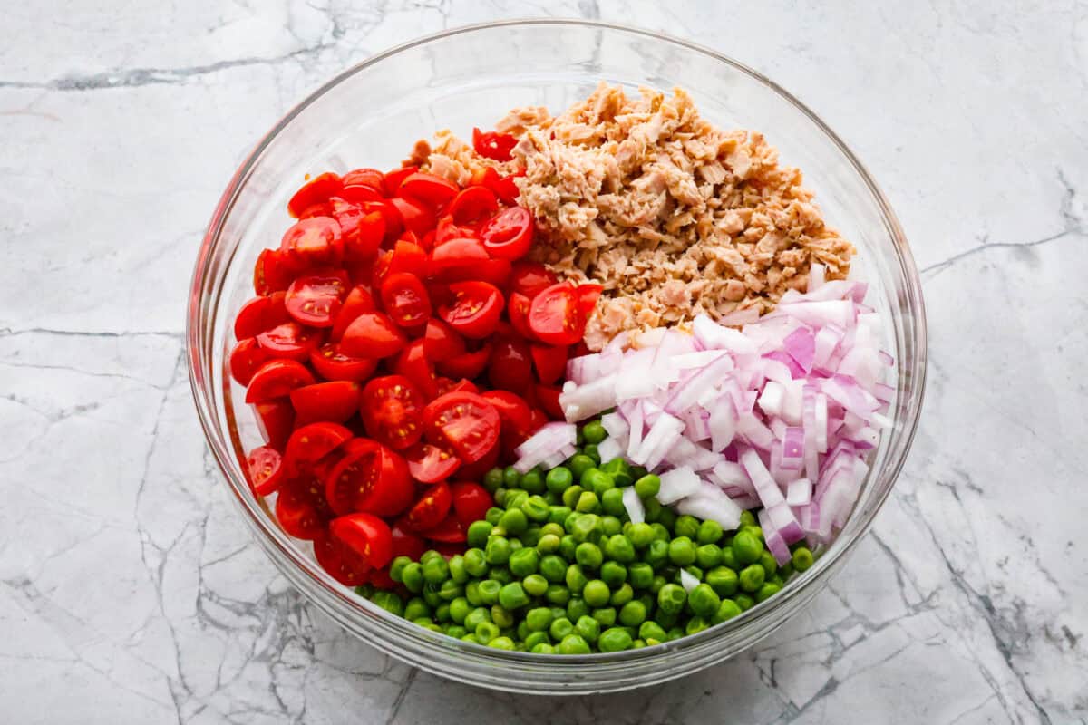Tuna pasta salad is a perfect protein-packed lunch or side dish! It combines tuna, veggies, and pasta then gets tossed in a creamy dill dressing. First photo of the salad ingredients in a bowl.